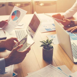 Ihmisiä teknologisten laitteiden ympärillä työympäristössä