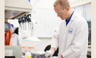 Ihminen laboratoriossa suojavaatteet päällä